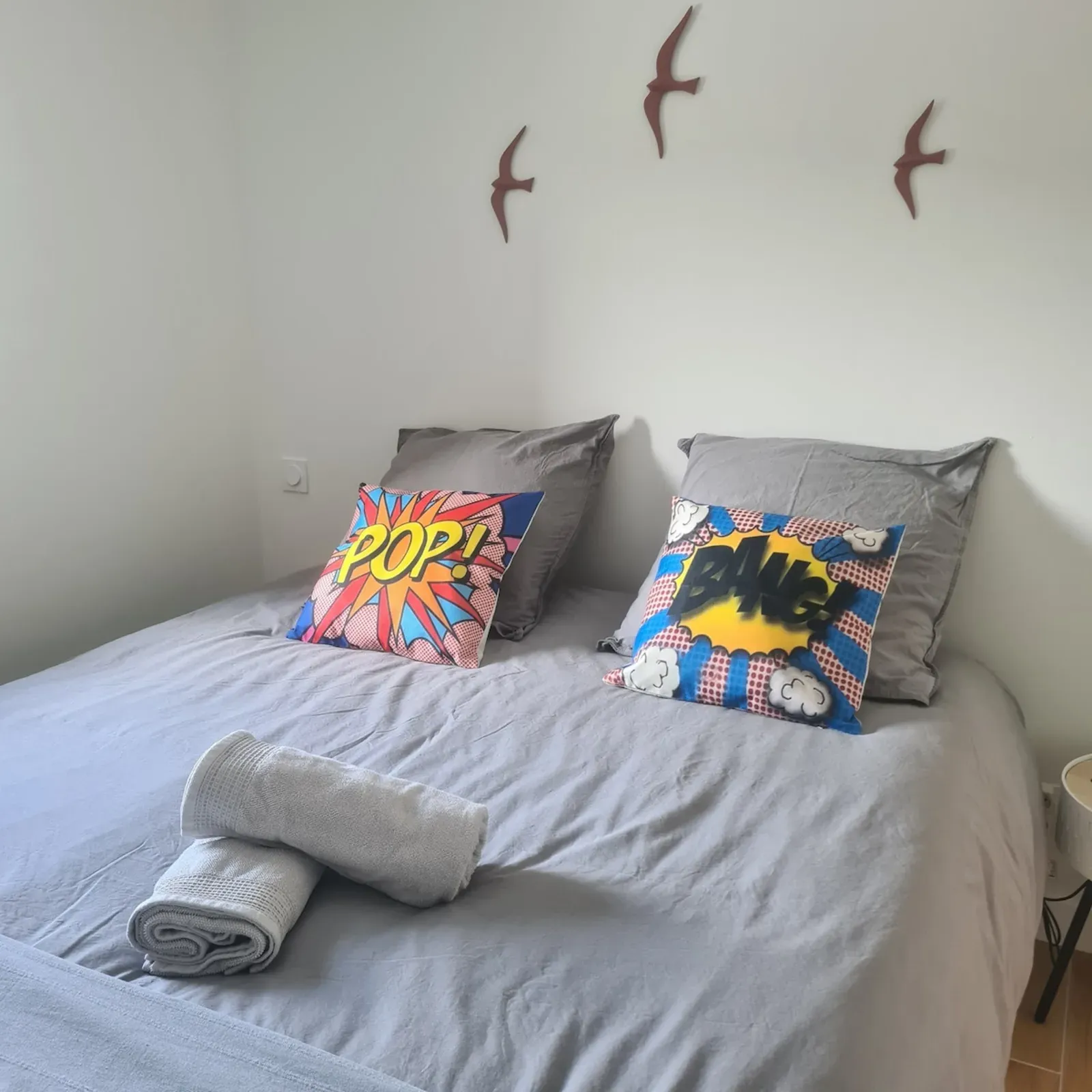 Double bed with comic-style cushions and decorative birds on the wall