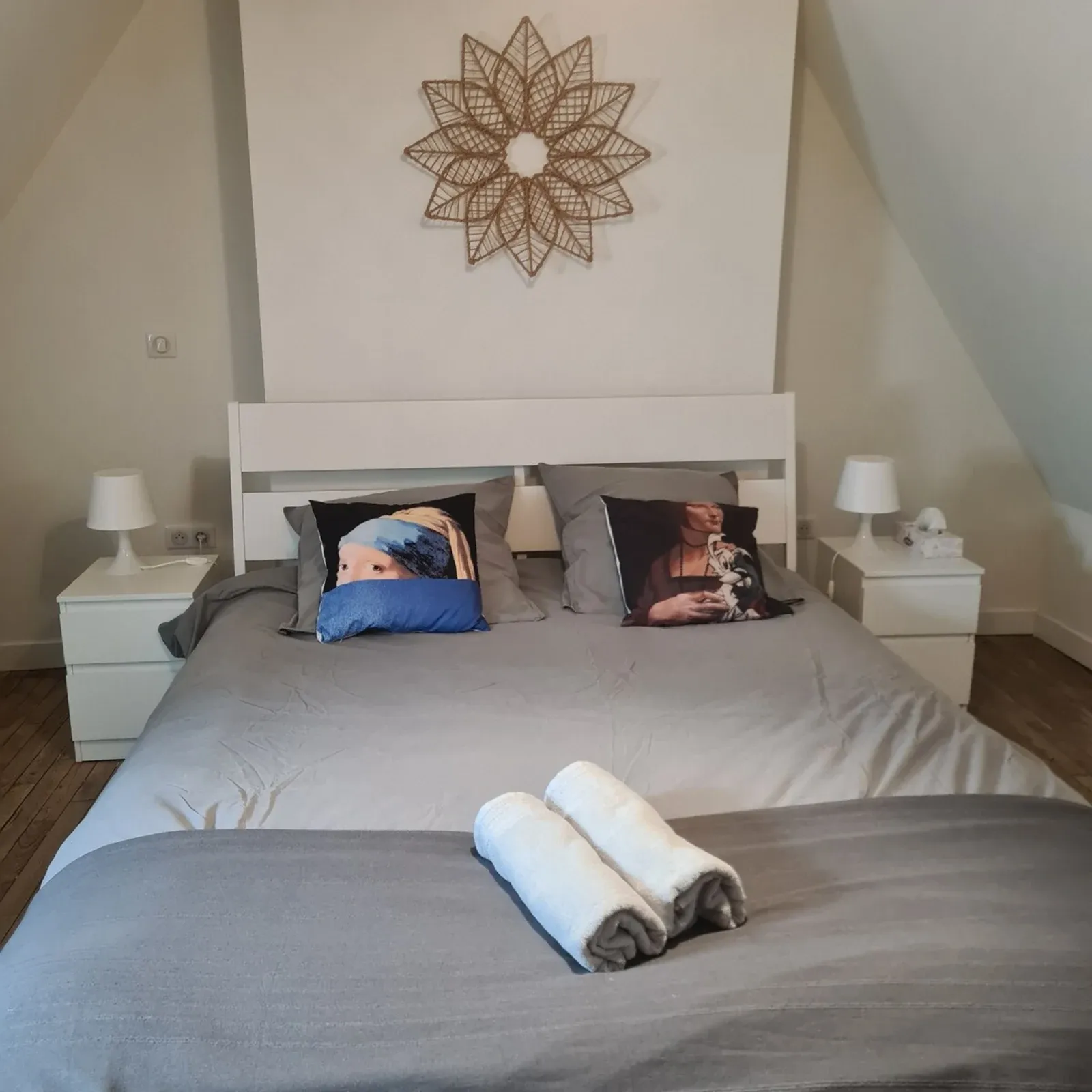 Attic bedroom with a double bed, white bedside tables and a rope rosette on the wall