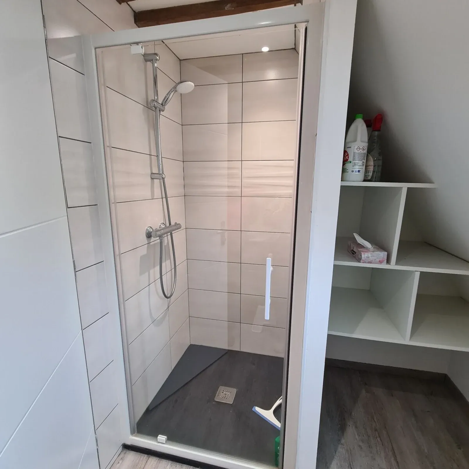 Attic shower room with a glass shower cubicle and shelves
