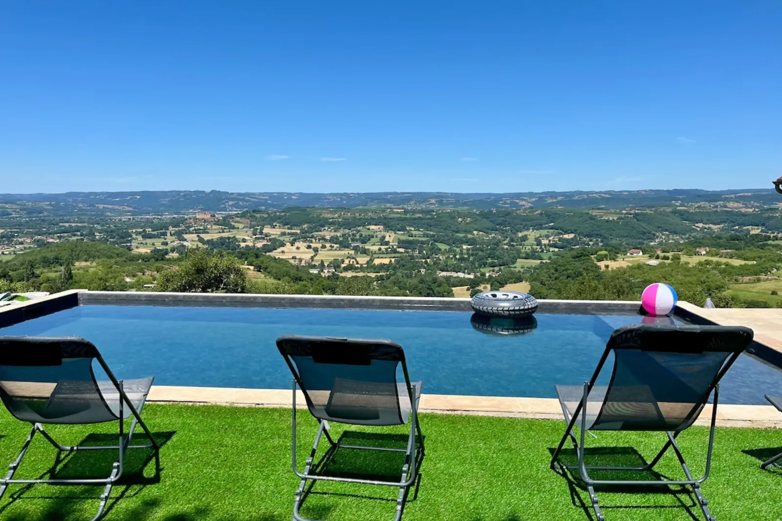 Piscine bordée de chiliennes sur une pelouse, face à la vallée de la Dordogne