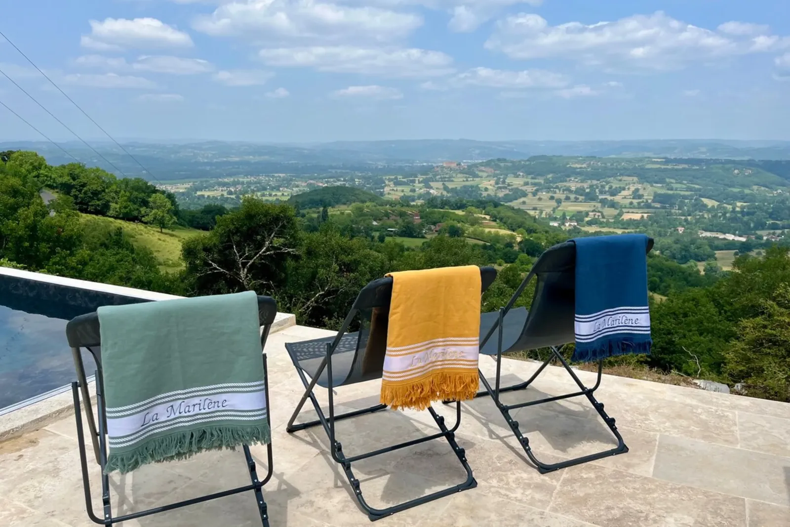Chiliennes et serviettes brodées « La Marilène » au bord de la piscine, face à la vallée