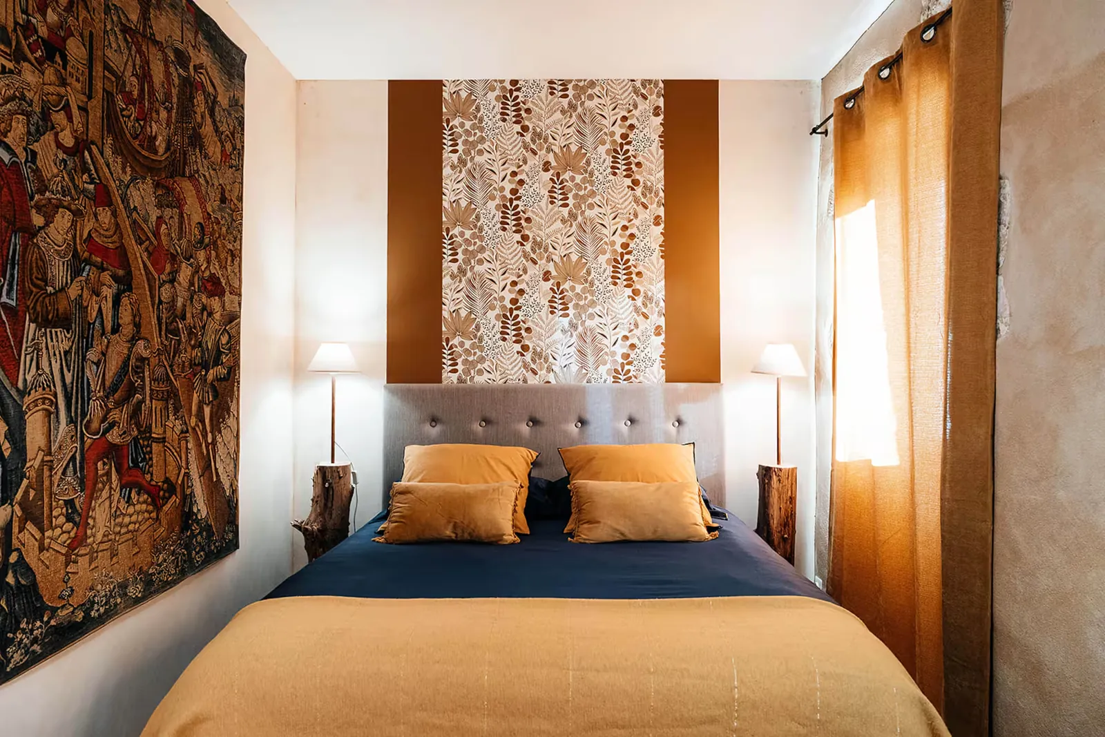 Chambre avec grand lit, tapisserie ancienne et rideaux couleur ocre