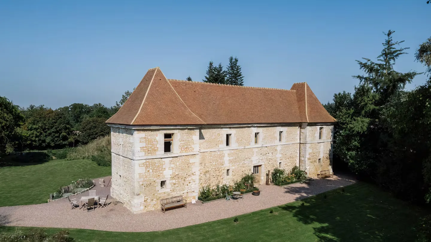 Façade en pierre du logis Louis XIII de La Motte Féodale, avec sa cour gravillonnée et son parc, au Mesnil-Jourdain