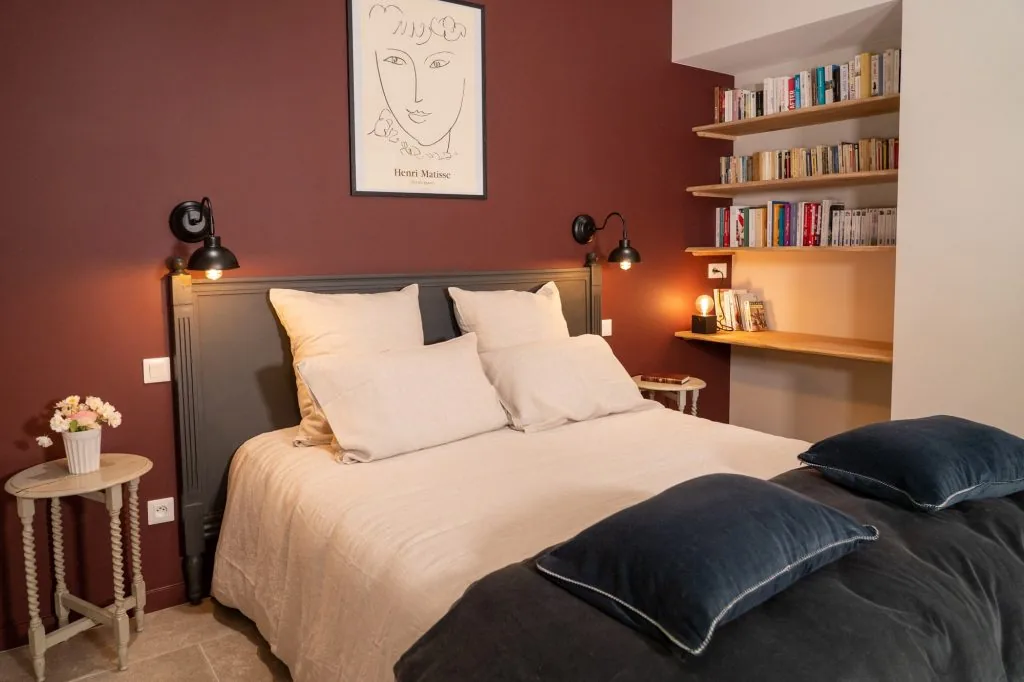 Burgundy-walled bedroom with a double bed and bookshelves, Le Clos d'Abrigeon