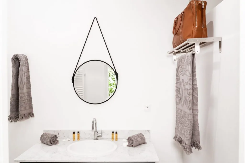 White bathroom with a marble washbasin and round mirror, Le Clos d'Abrigeon