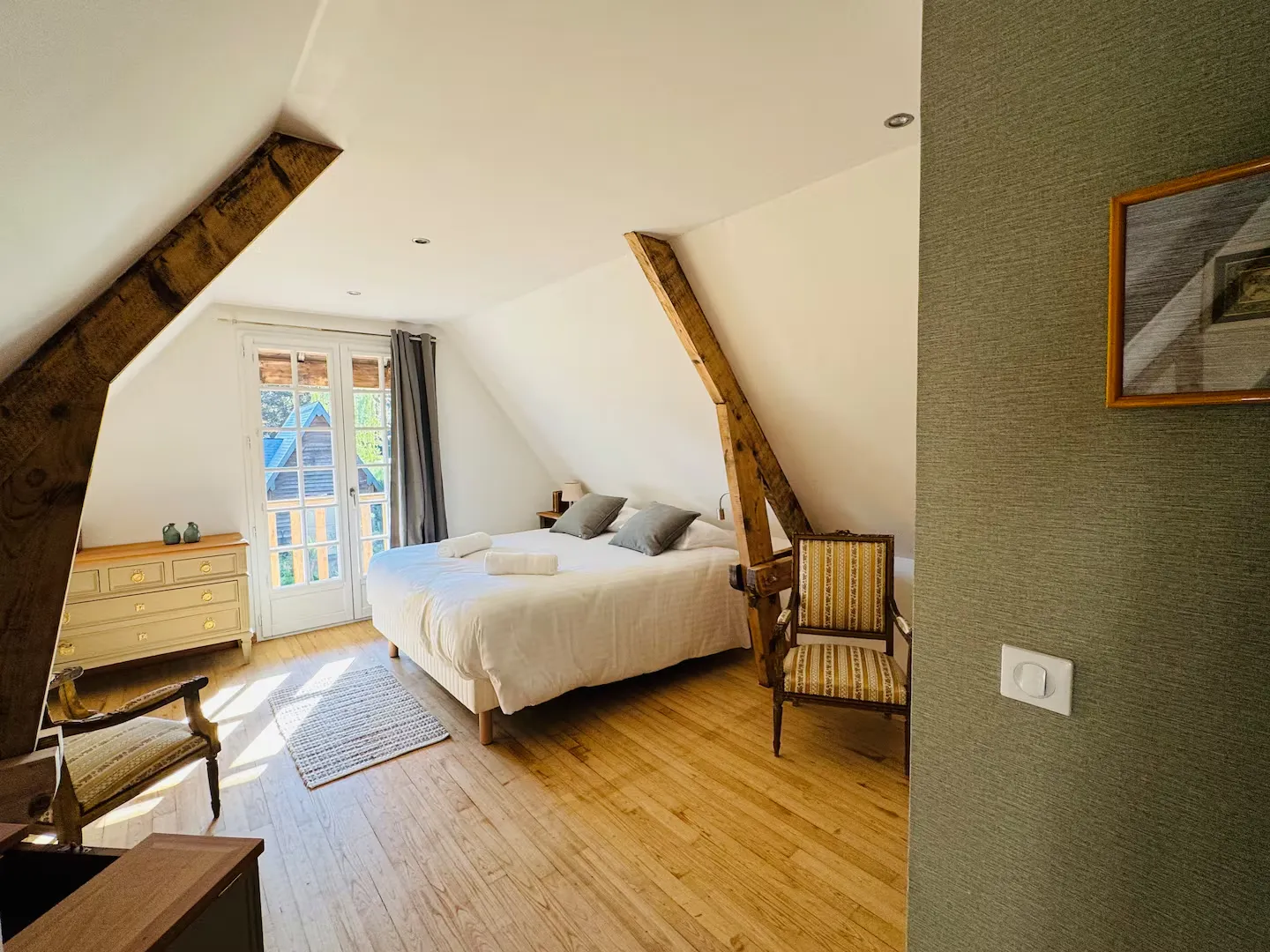 Chambre mansardée sous poutres apparentes, avec grand lit et porte-fenêtre, Le Clos du Veneur