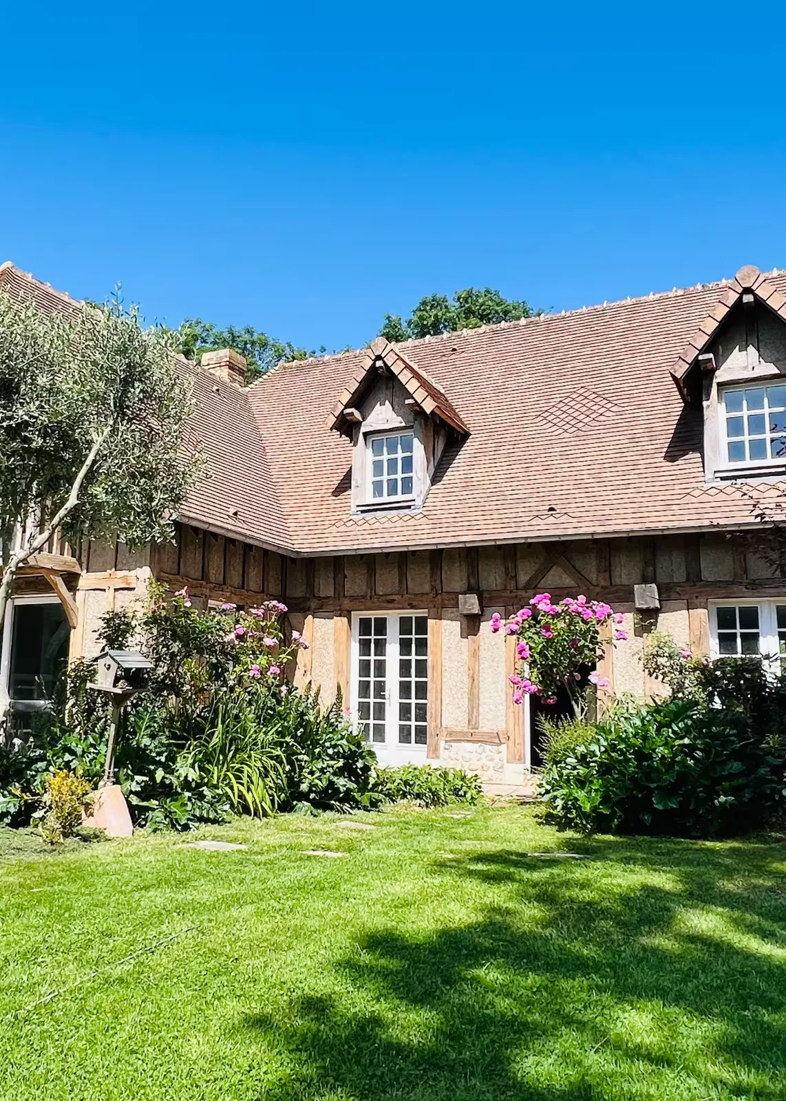 Façade à colombages et lucarnes, massifs fleuris et pelouse, Le Clos du Veneur
