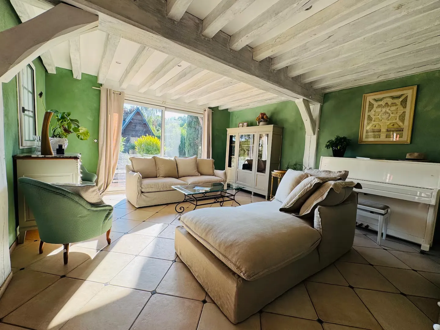 Salon lumineux aux poutres blanchies, avec canapés, piano et baie vitrée ouverte sur le jardin, Le Clos du Veneur