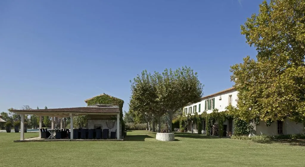 Façade du mas aux volets verts et pergola sur la pelouse, Mas de la Galégière à Arles