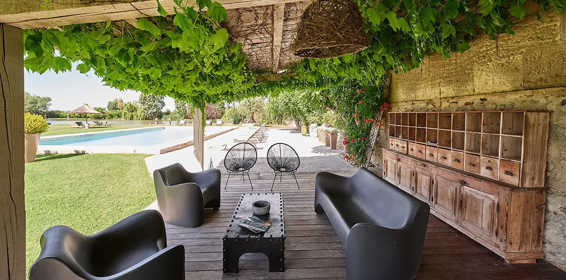 Salon d'extérieur sous une treille, avec vue sur la piscine du mas