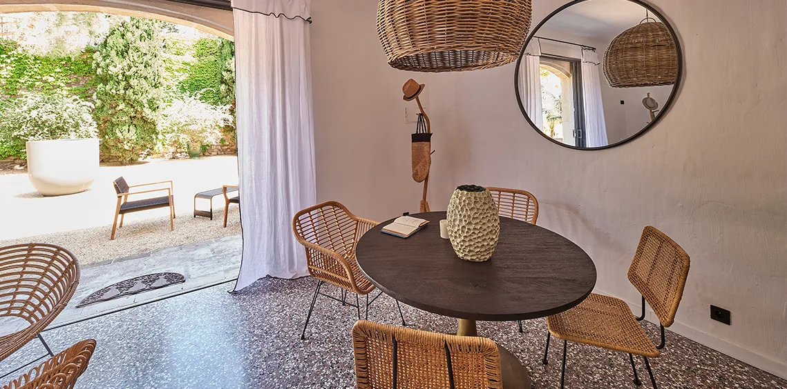 Séjour du Pin avec table ronde et chaises en rotin, ouvert sur la terrasse