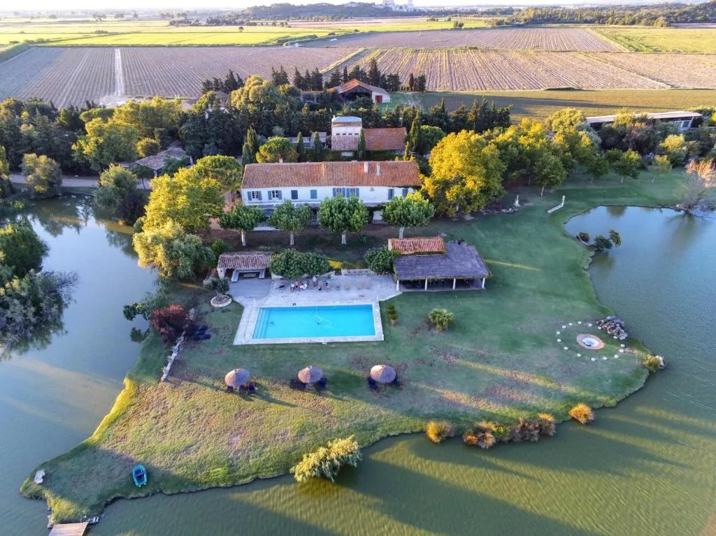 Vue aérienne du Mas de la Galégière à Arles, entouré d'étangs, avec sa piscine et son jardin