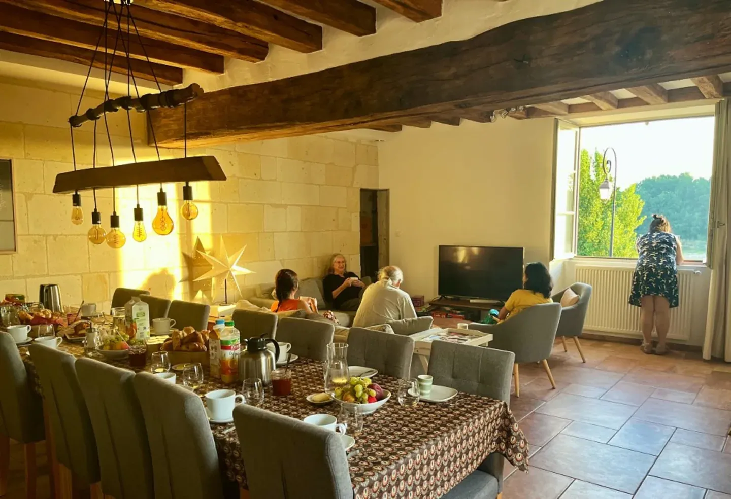 Breakfast in the beamed living room with tufa walls, window open onto the Loire, Logis Escale