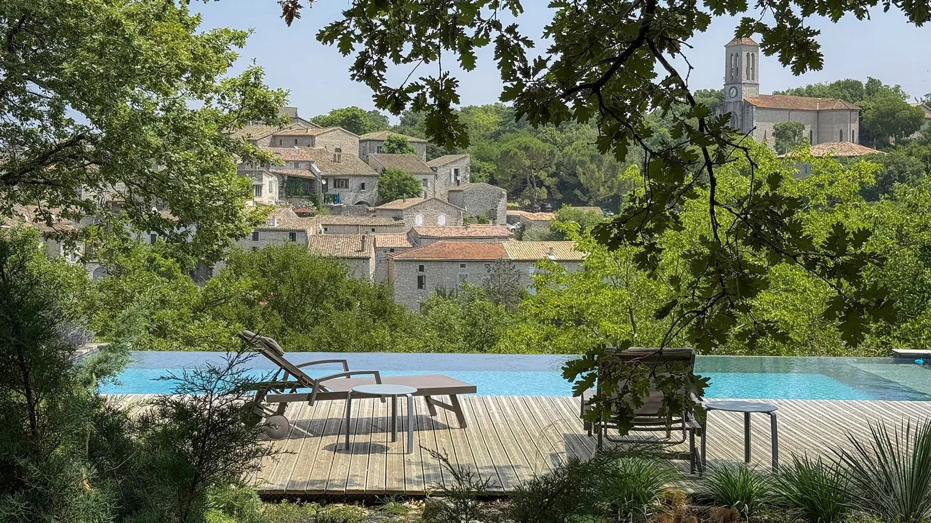 Infinity pool and sun loungers facing the medieval village of Balazuc, Maison Chassel