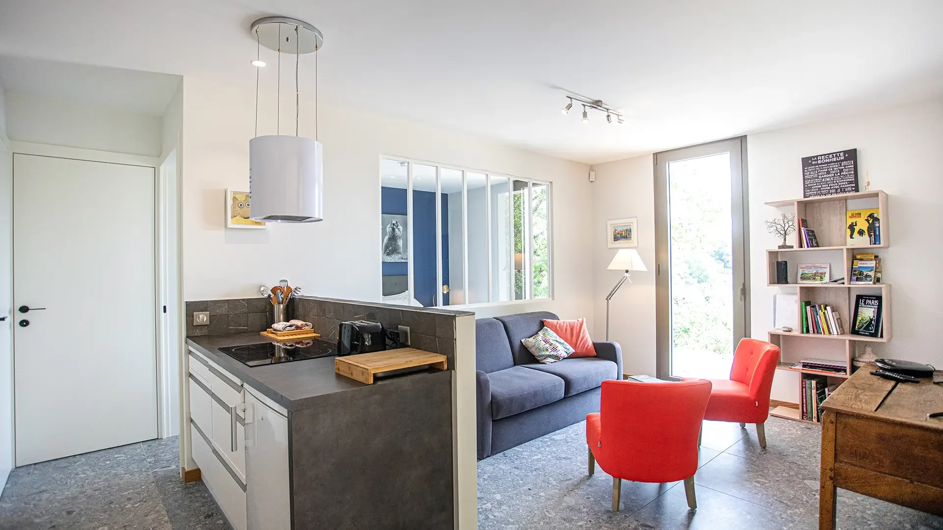 Bright living room with open kitchen, sofa and red armchairs, Maison Chassel gîte