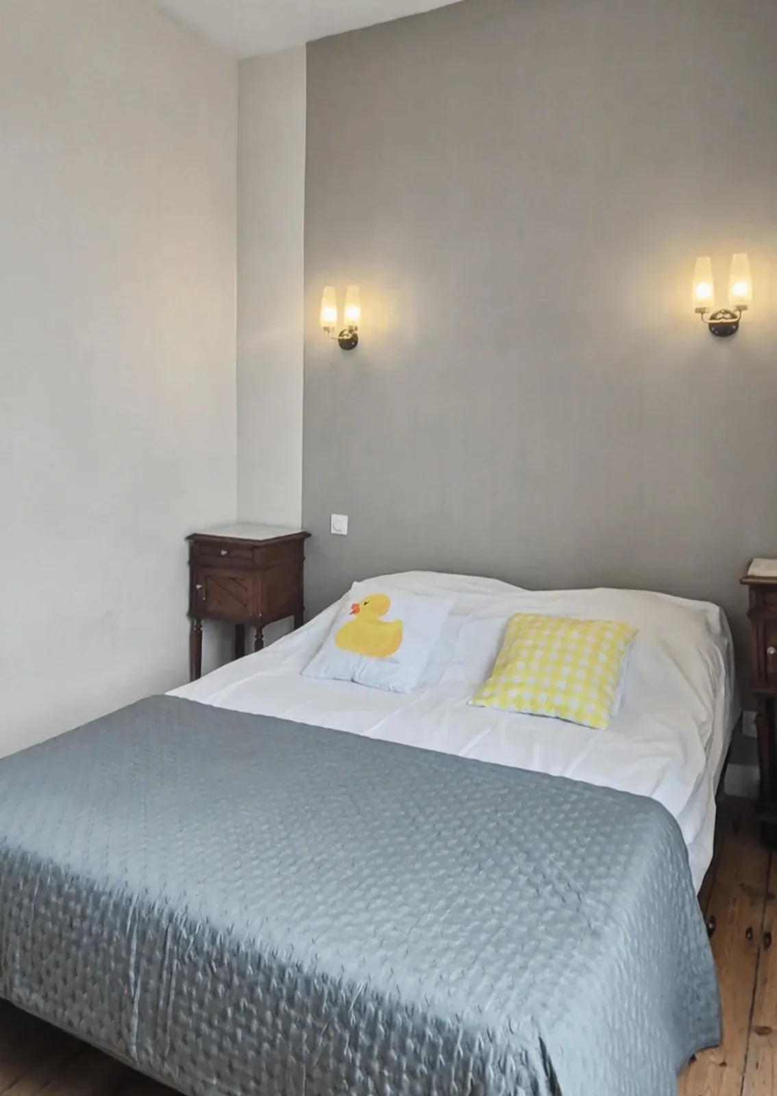 Chambre avec lit double, jeté gris et coussins jaunes