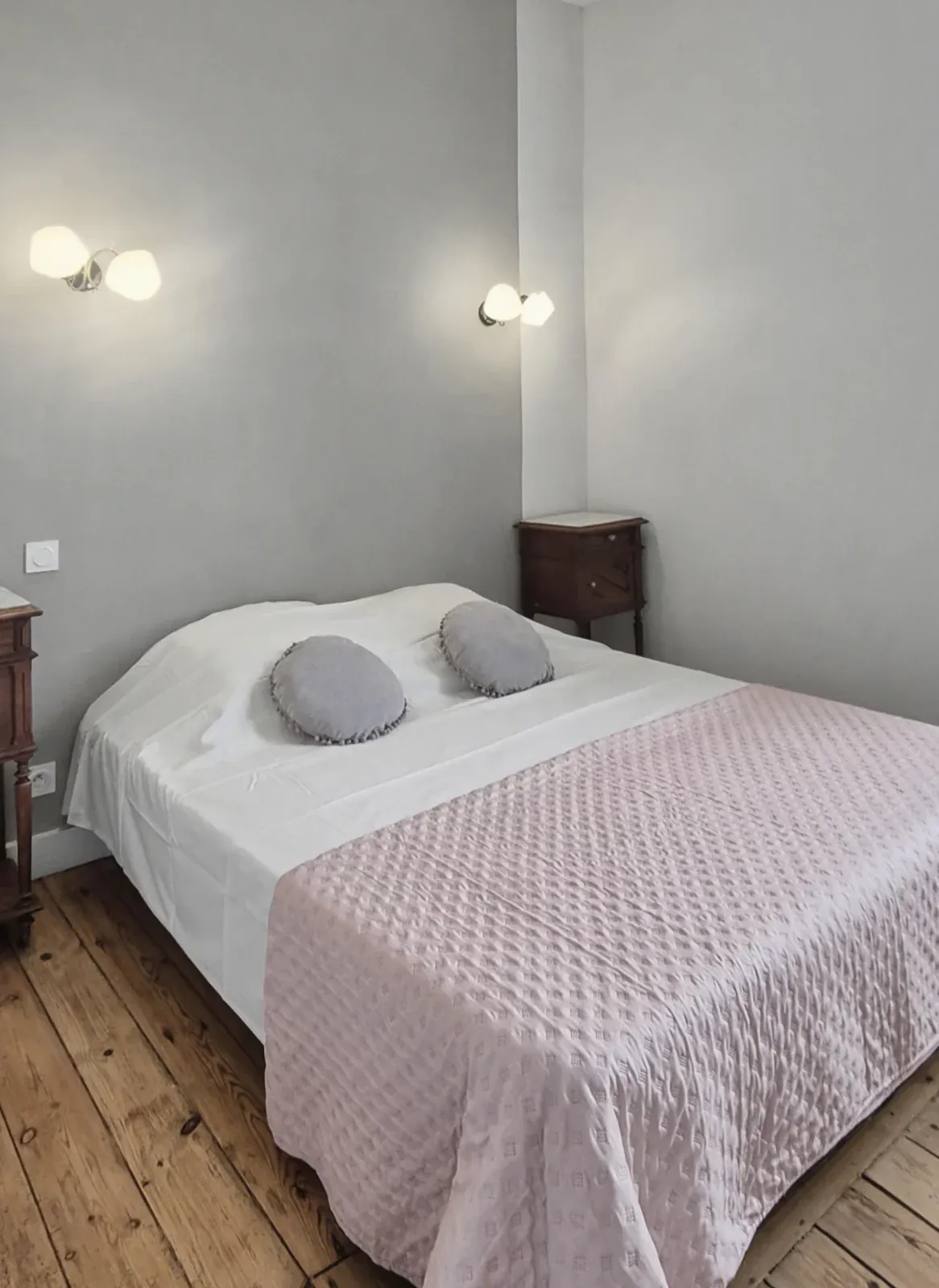 Chambre avec lit double, jeté rose et coussins gris