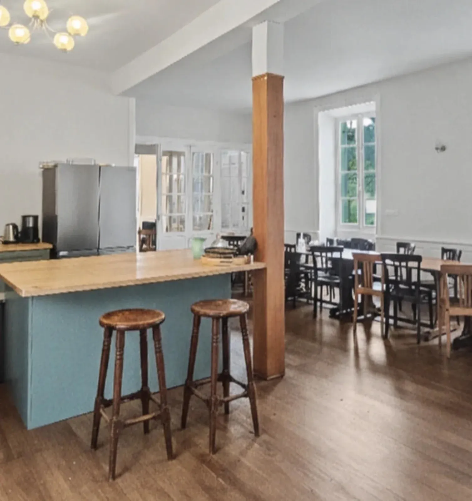 Cuisine avec îlot bleu et tabourets en bois, ouverte sur la salle à manger