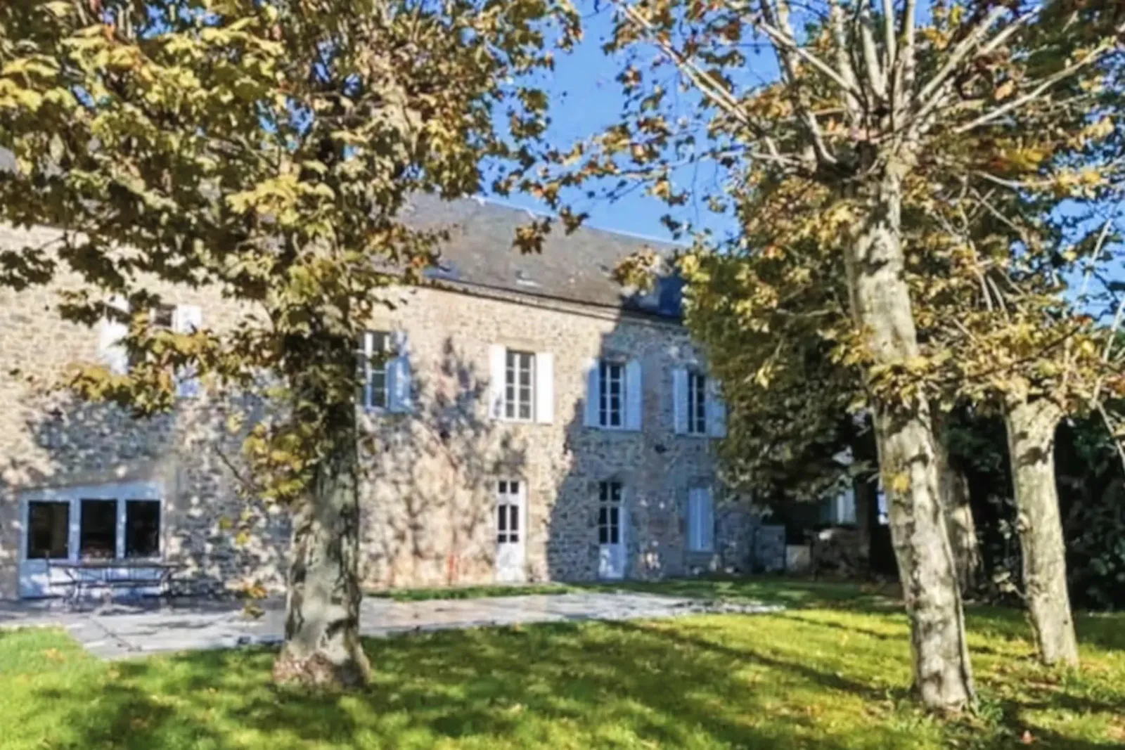 Jardin arboré de grands platanes devant la façade en pierre