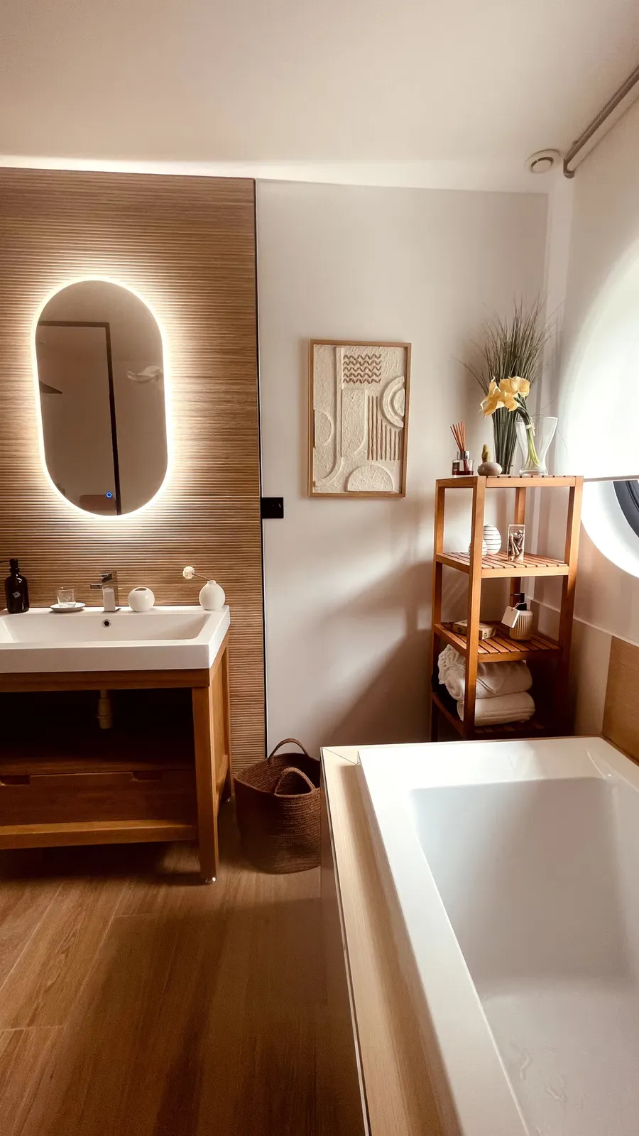 Salle de bains avec baignoire, vasque sur meuble en bois et étagère de serviettes