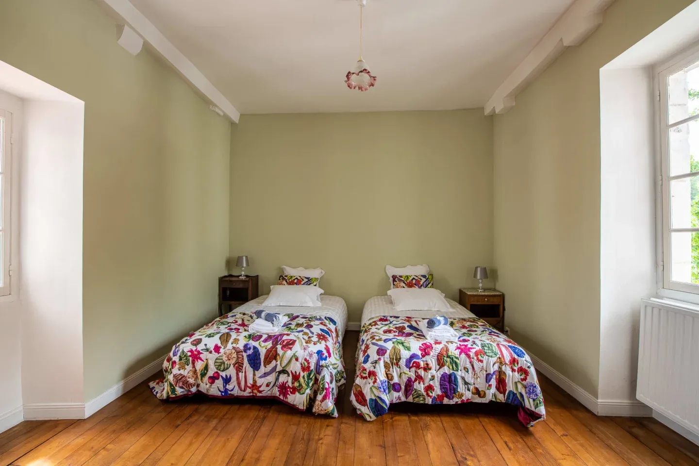Chambre lumineuse avec deux lits simples et dessus-de-lit fleuris, Maison Luroa