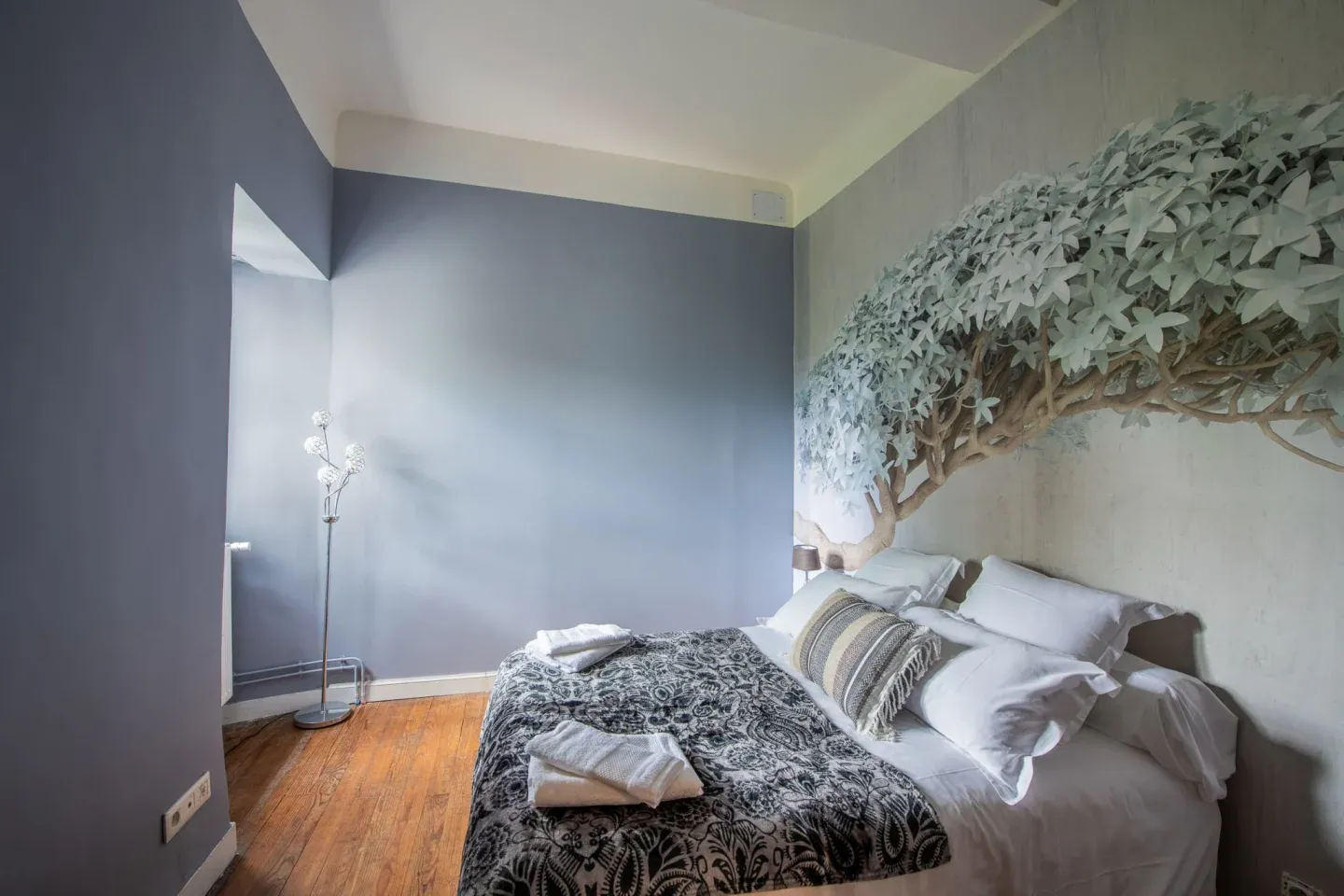 Chambre au décor zen avec fresque d'arbre et parquet, Maison Luroa
