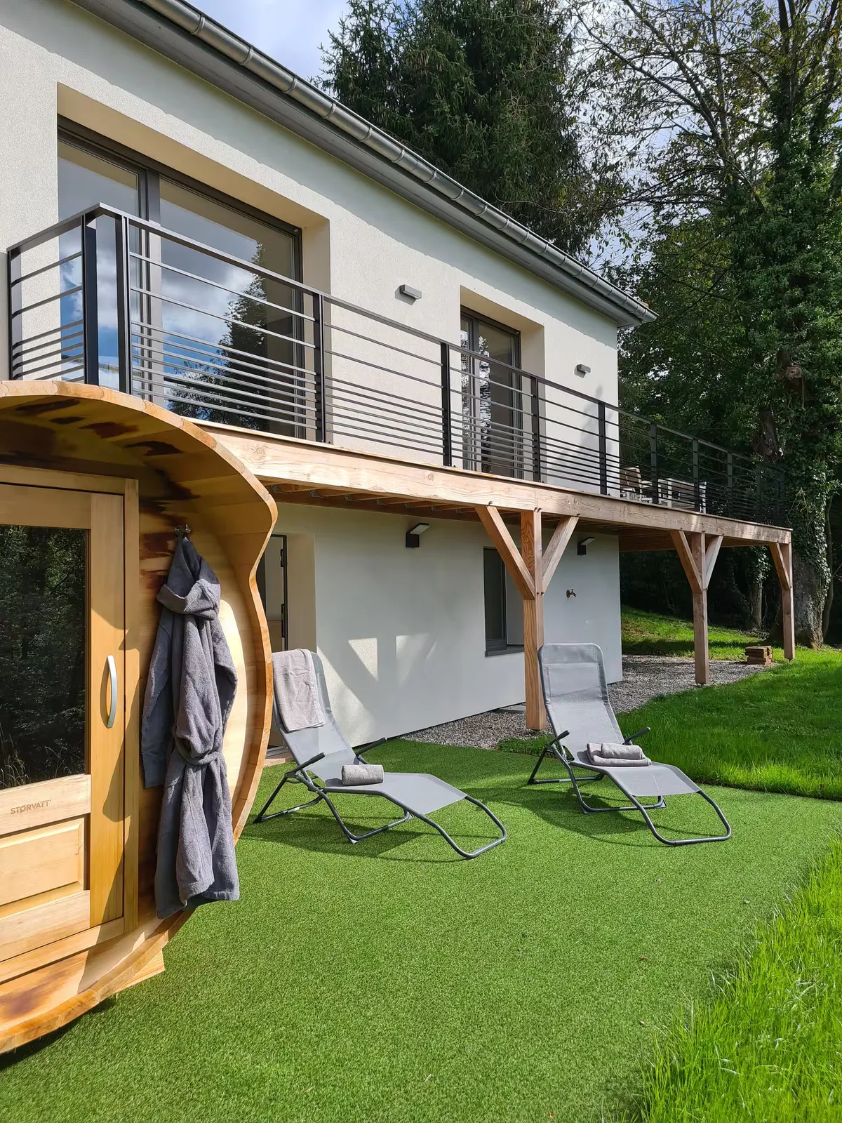 Façade du gîte Sapin Zen avec sauna tonneau et transats sur la pelouse, sous le balcon