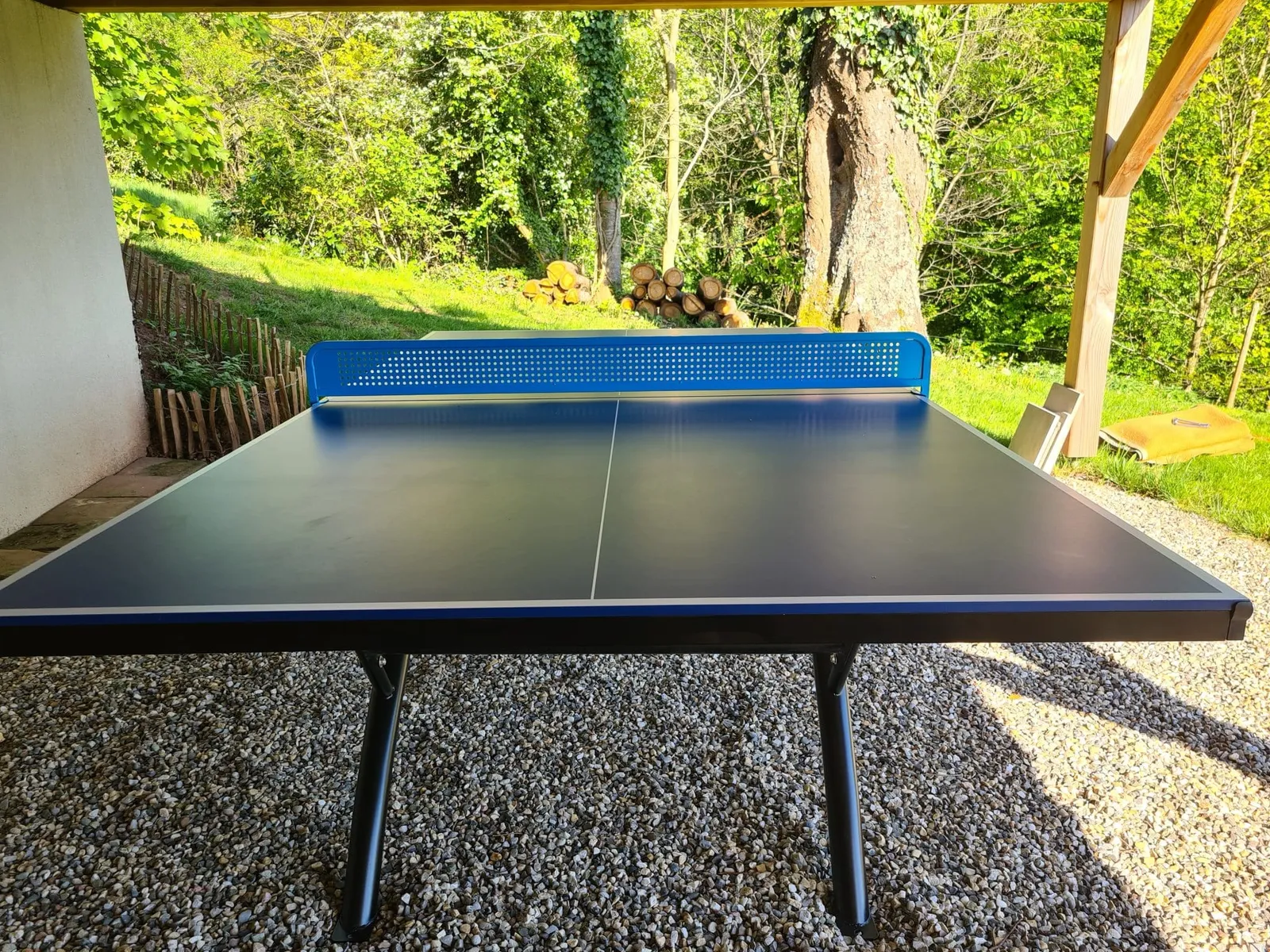 Table de ping-pong extérieure à l'abri sous la terrasse, au bord du jardin, gîte Sapin Zen